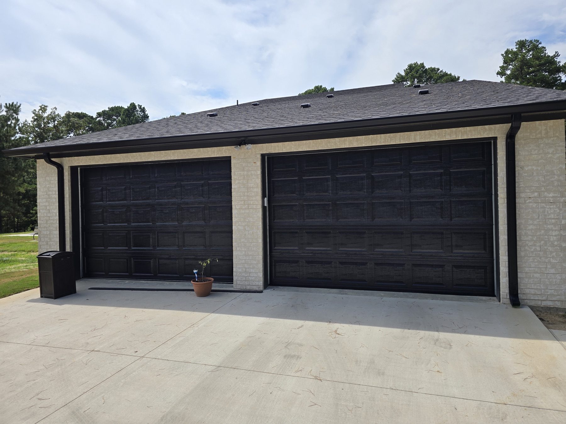 Two dark carriage-style doors on a brick garage.